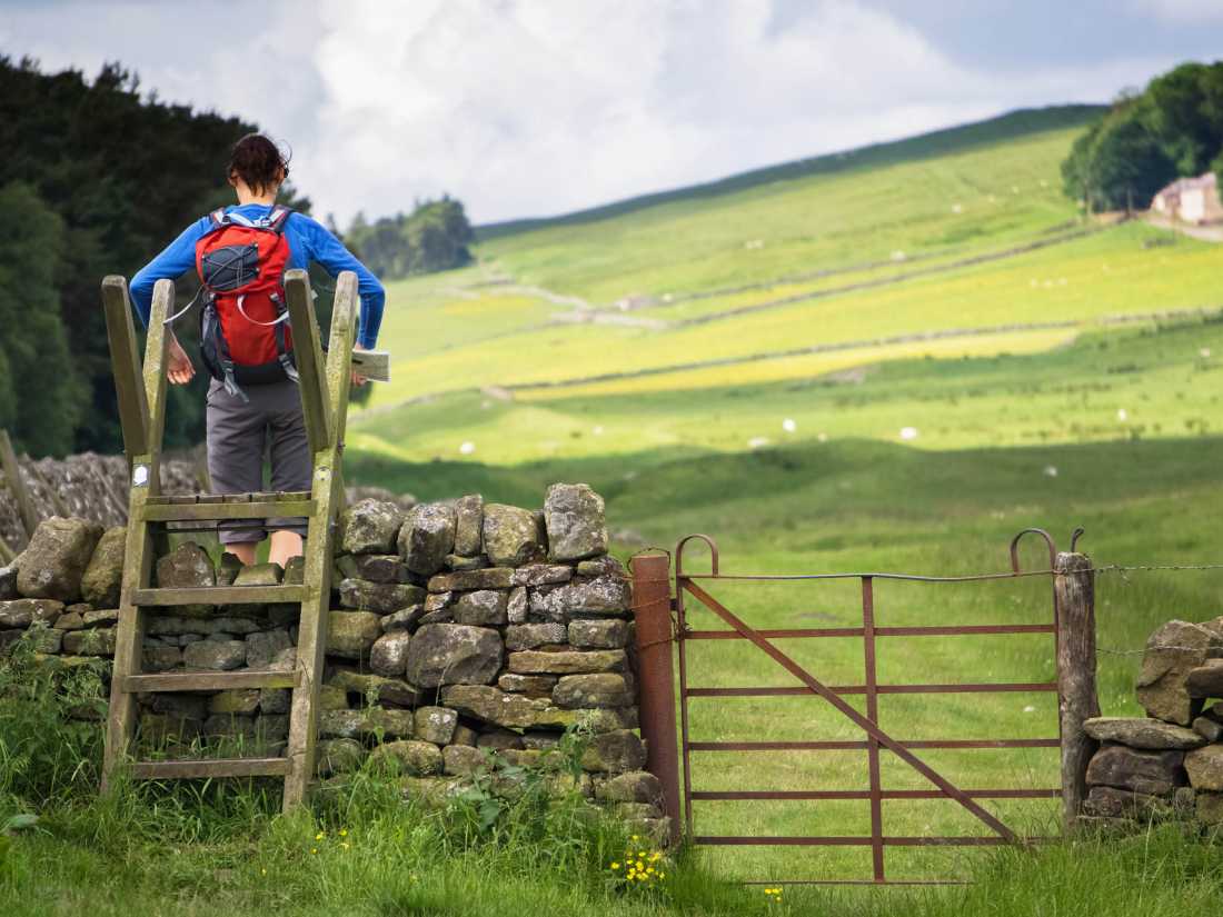 A hiker crossing a stile on the Hadrian's Wall Walk in Northumberland, Northeast of England, UK. |  Duncan Andison